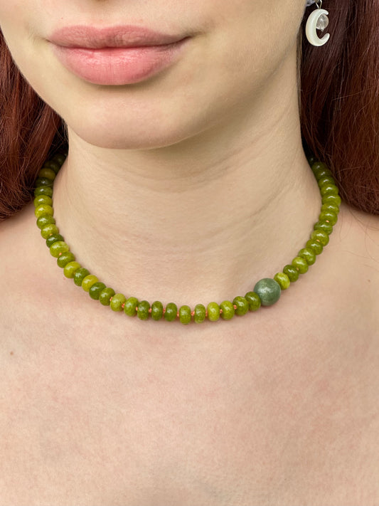Close-up of a person wearing a green beaded necklace.
