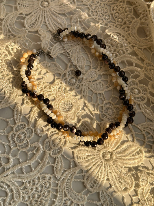 Necklace with black and beige beads on a lace background