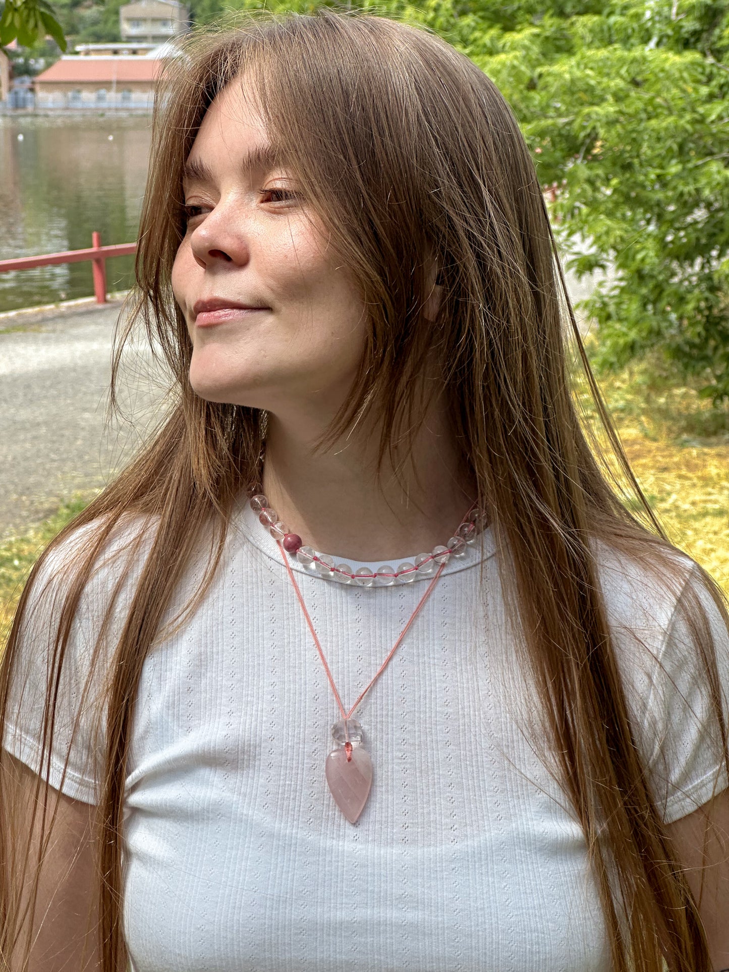 Woman wearing a necklace with a pink pendant outdoors