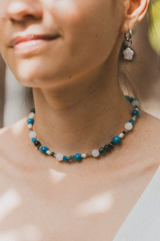 Close-up of a woman wearing a beaded necklace with a blurred background