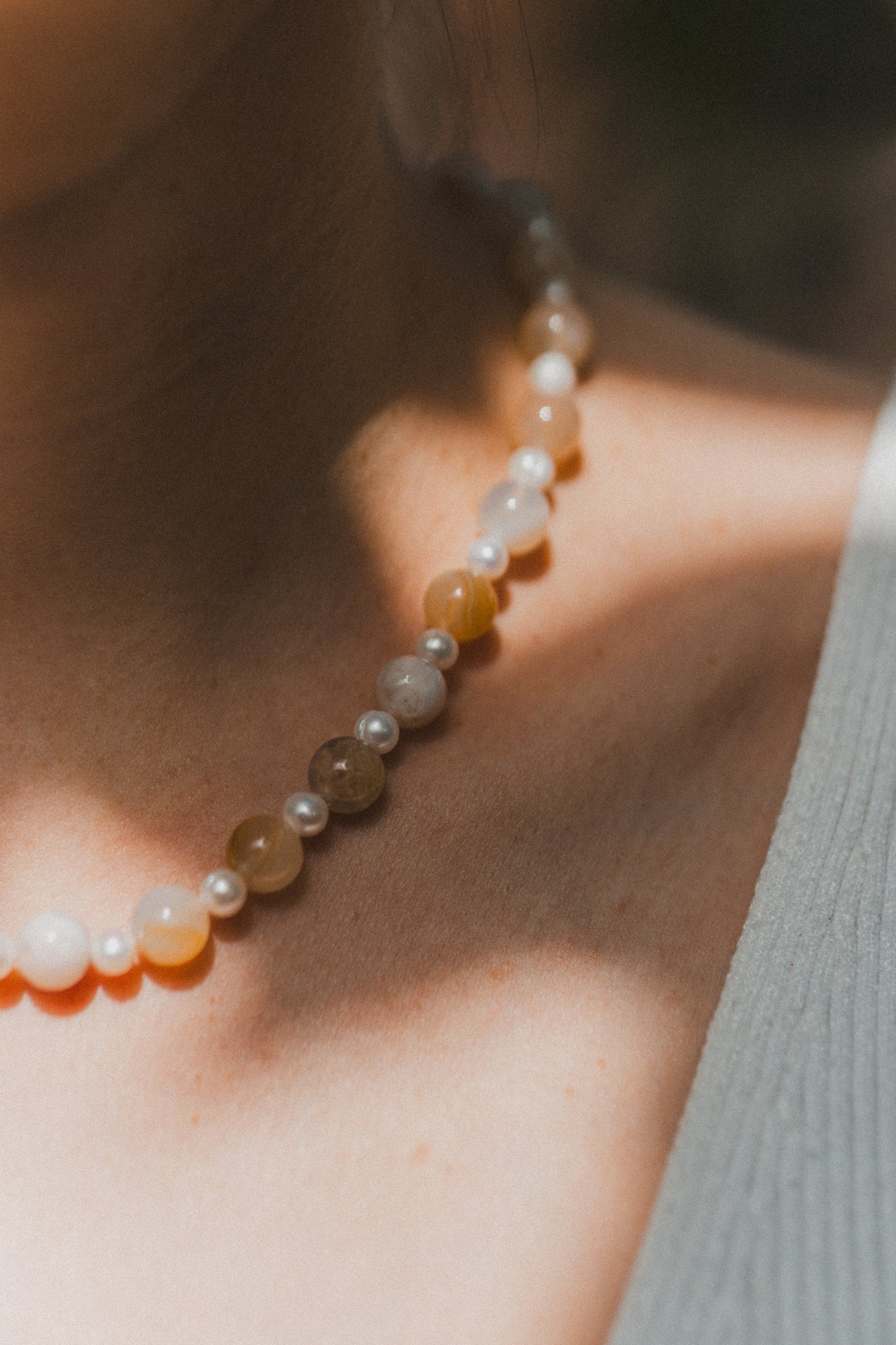 Close-up of a person wearing a beaded necklace with a blurred background