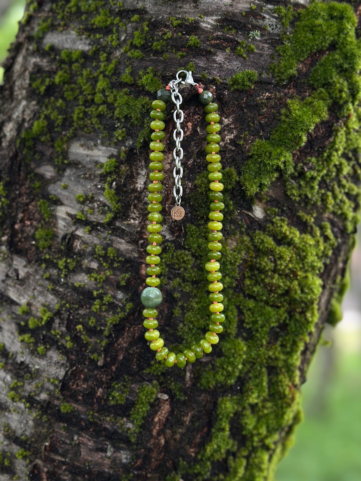 Green beaded necklace on a mossy tree branch