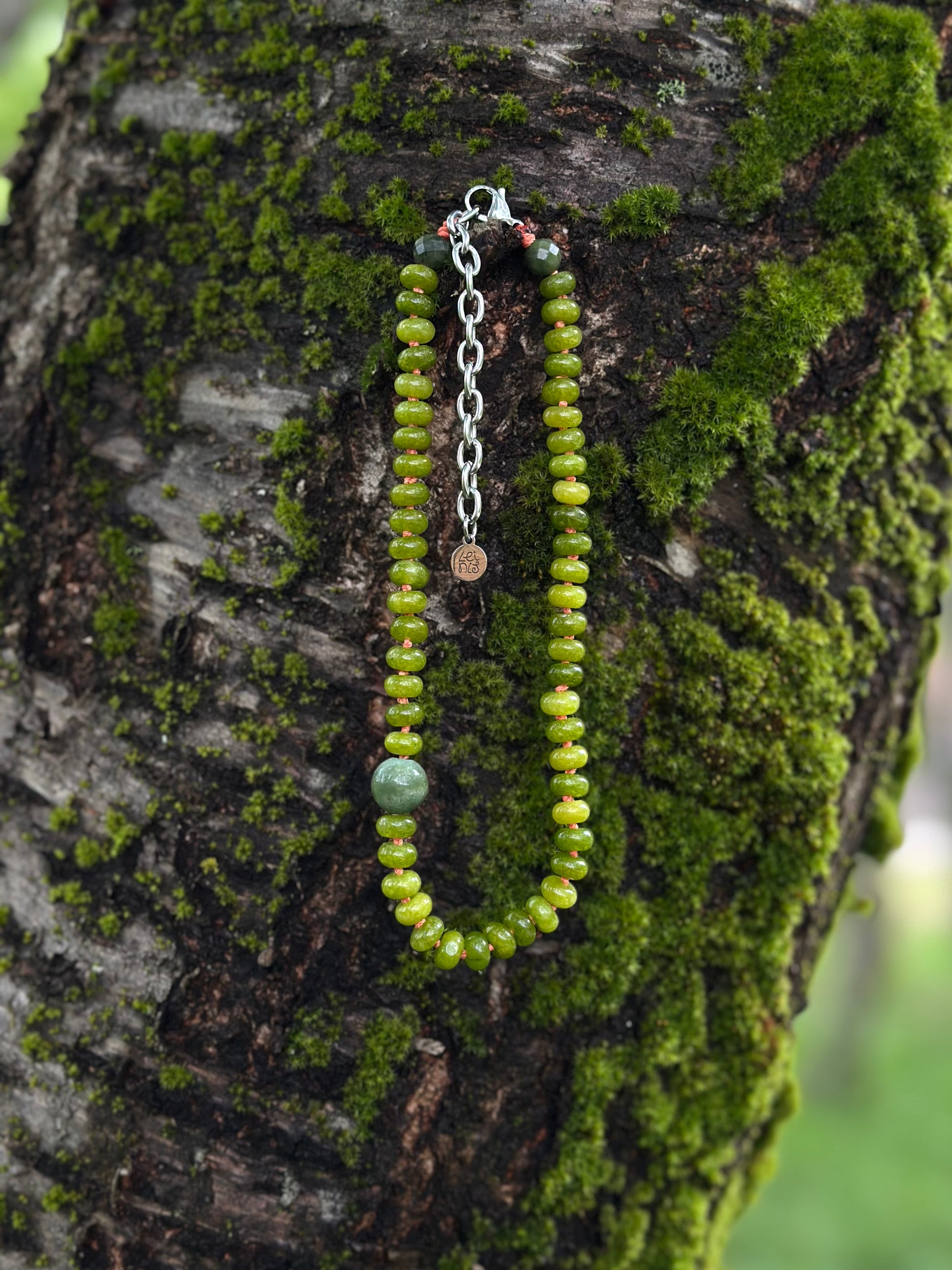 Green beaded necklace on a mossy tree branch
