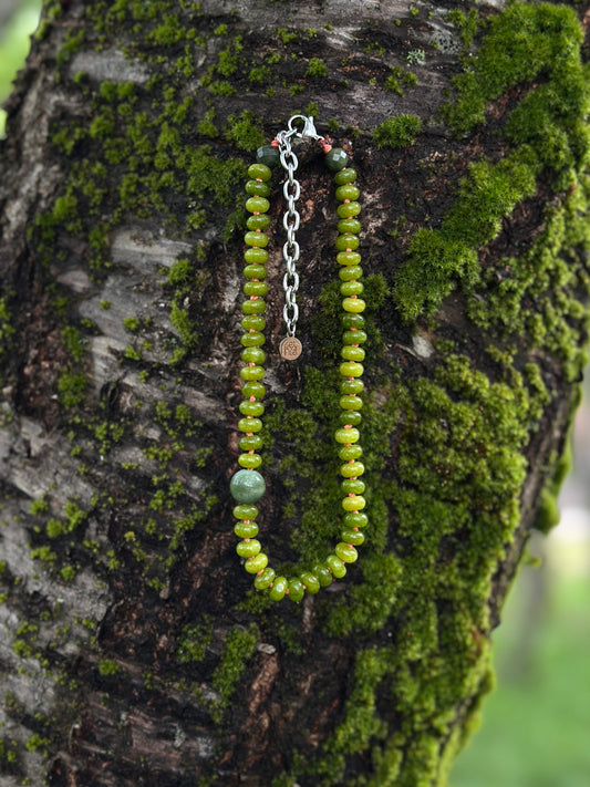 Green beaded necklace on a mossy tree branch