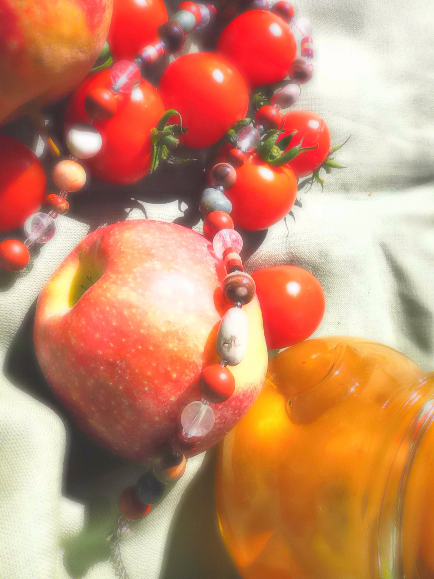 Close-up of apples, tomatoes, and a jar of honey on a reflective surface.
