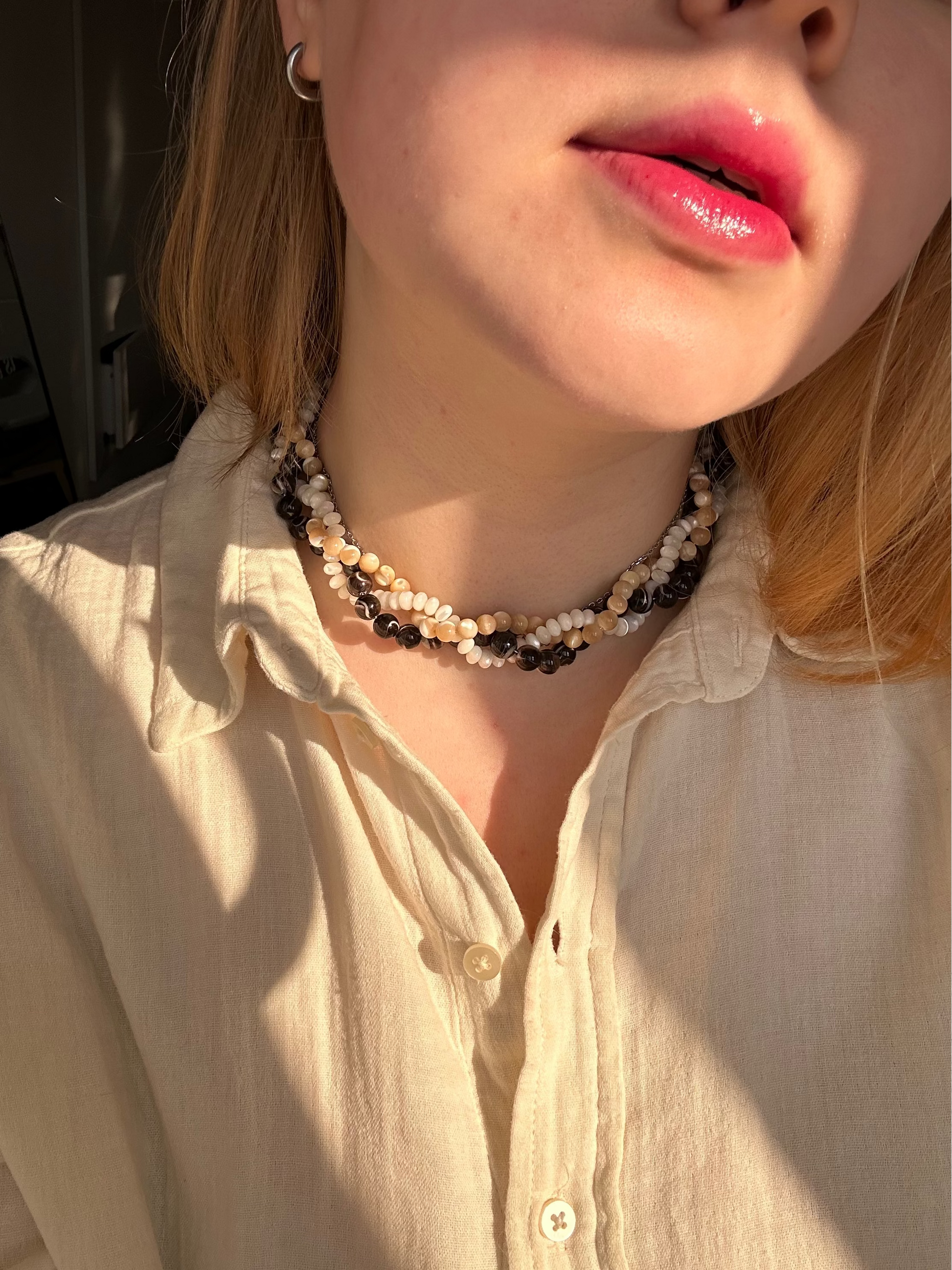 Close-up of a person wearing a beaded necklace with a blurred background