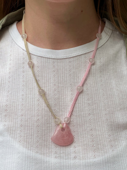 Necklace with a pink pendant worn by a person on a white shirt