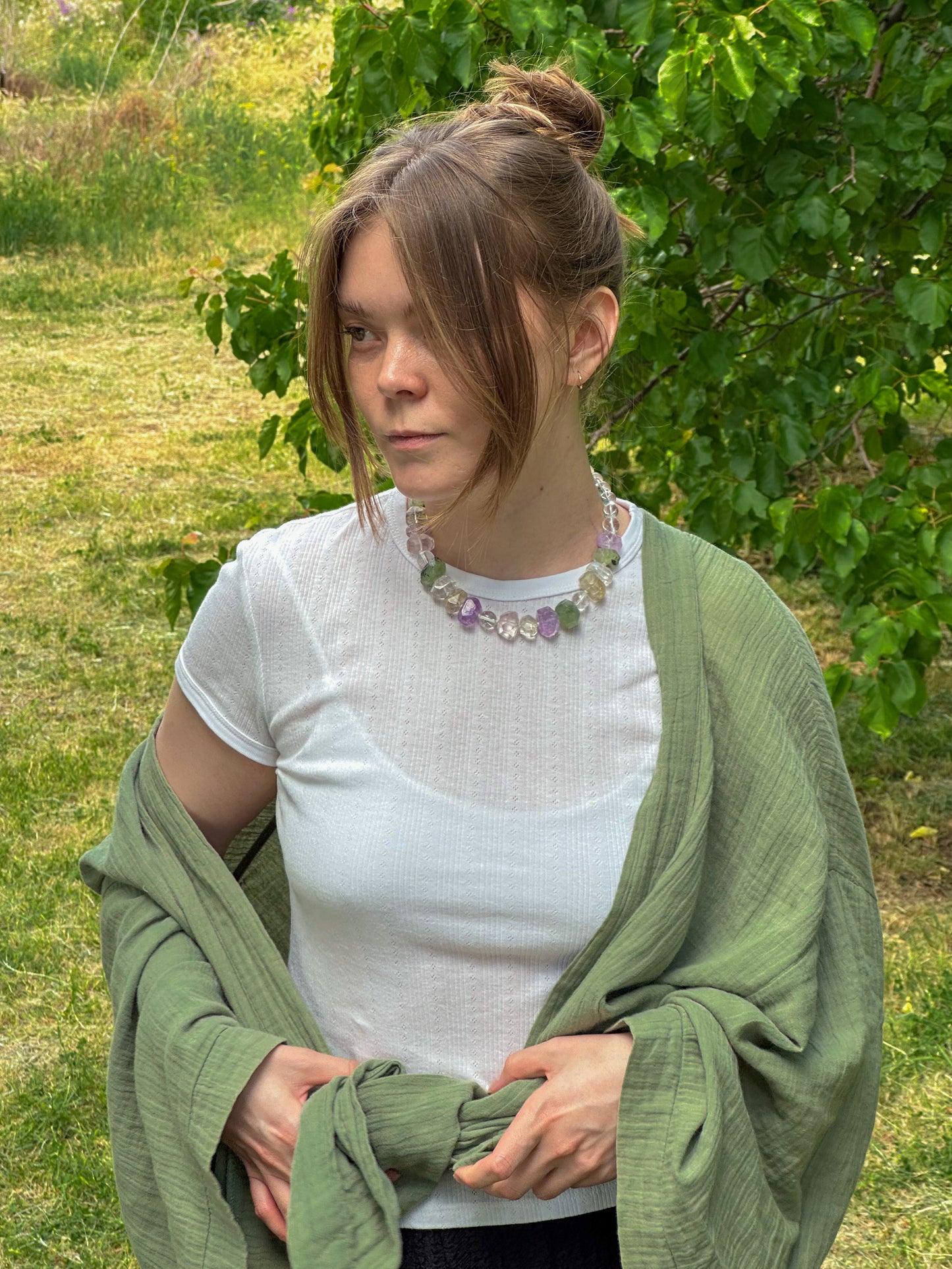 Woman wearing a green shawl and white top in a grassy outdoor setting