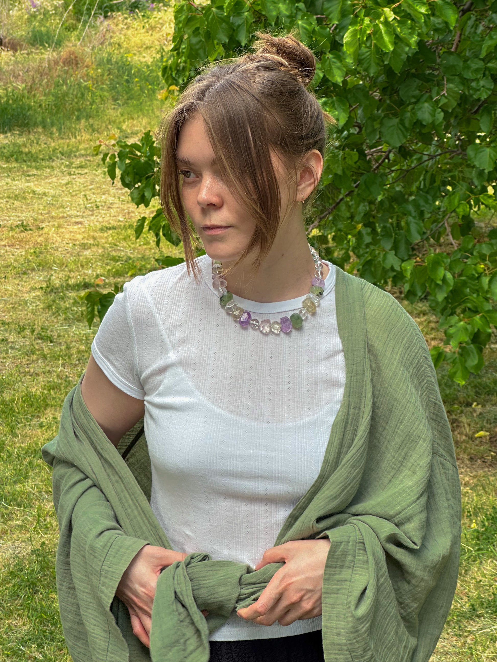Woman wearing a green shawl and white top in a grassy outdoor setting