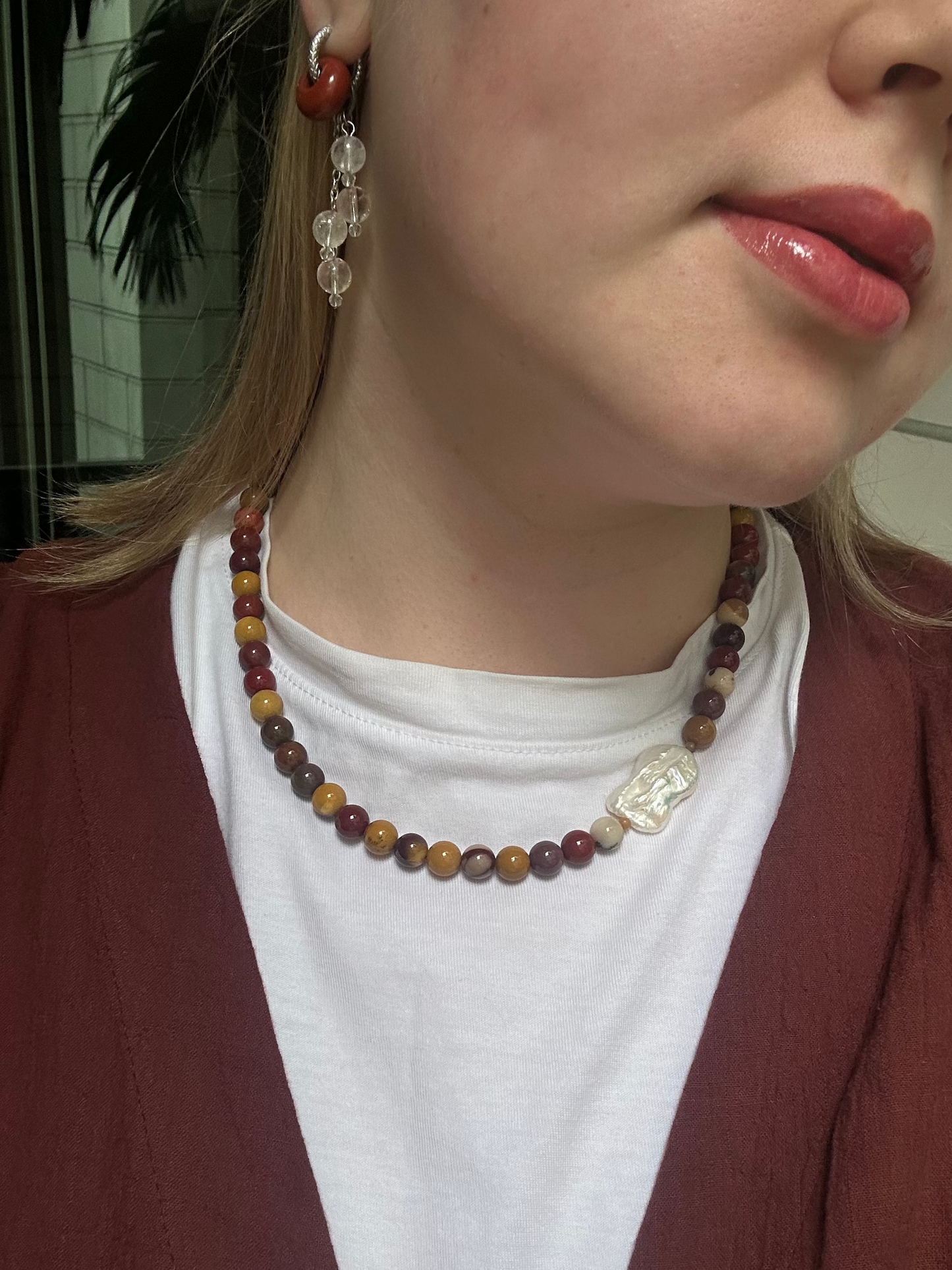 Close-up of a person wearing a beaded necklace and earrings.