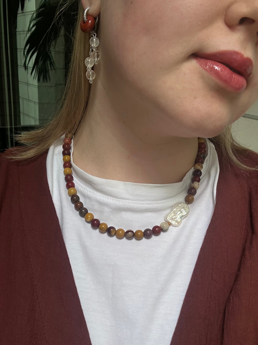 Close-up of a person wearing a beaded necklace and earrings.