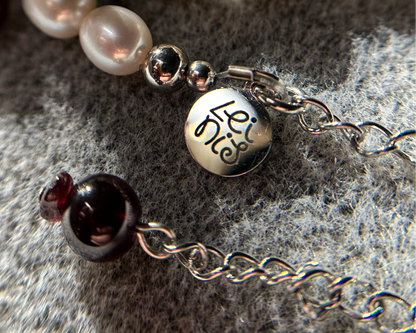 Pearl and gemstone bracelet charm on a textured surface