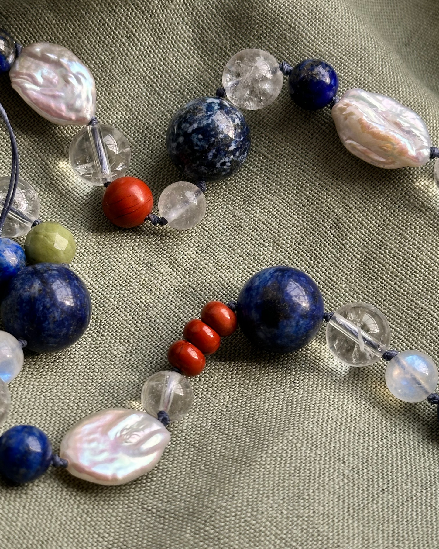Necklace with various beads on a textured fabric background