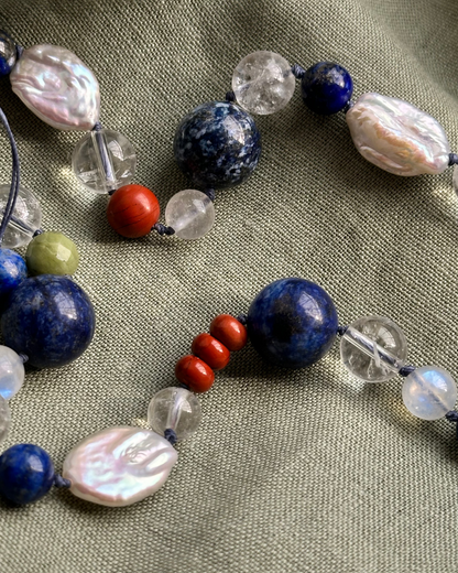 Necklace with various beads on a textured fabric background