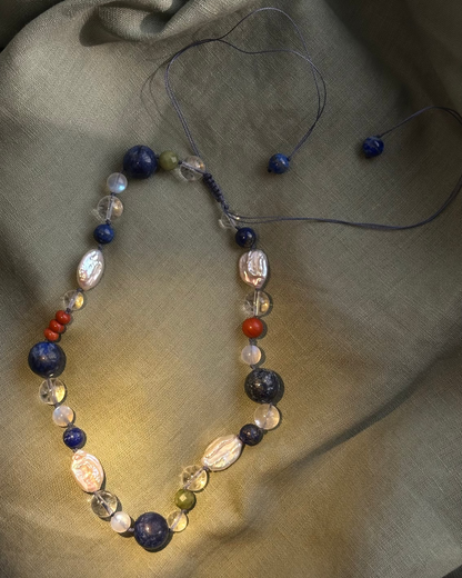 Necklace with multicolored beads on a textured fabric background