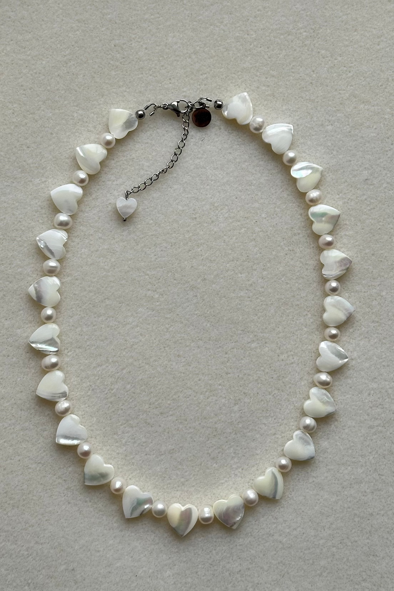 Necklace with heart-shaped pearls on a light gray background