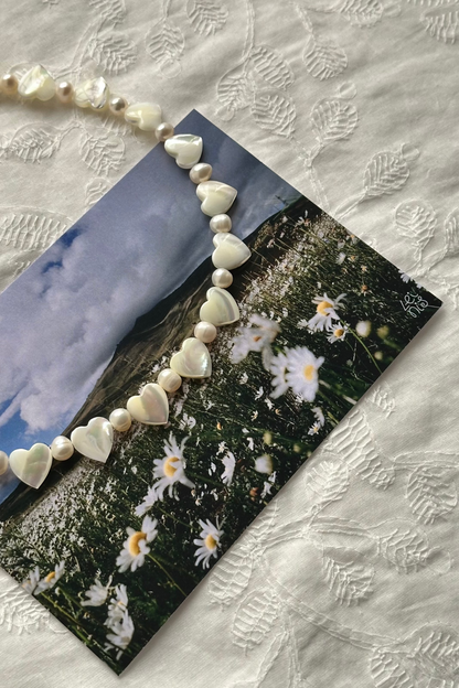 Decorative card with heart beads and floral design on a textured fabric background