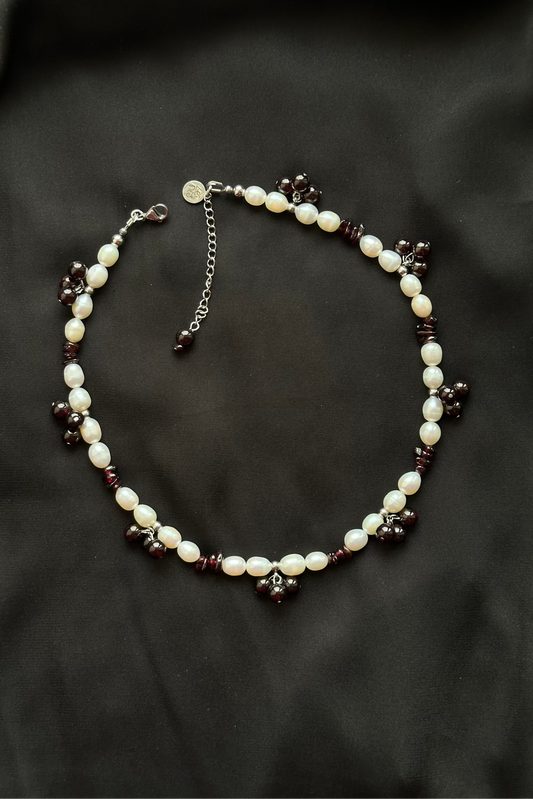Pearl and dark bead necklace on a black background
