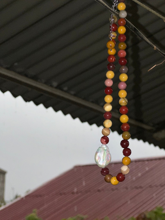 Beaded necklace with a large pearl pendant hanging from a roof