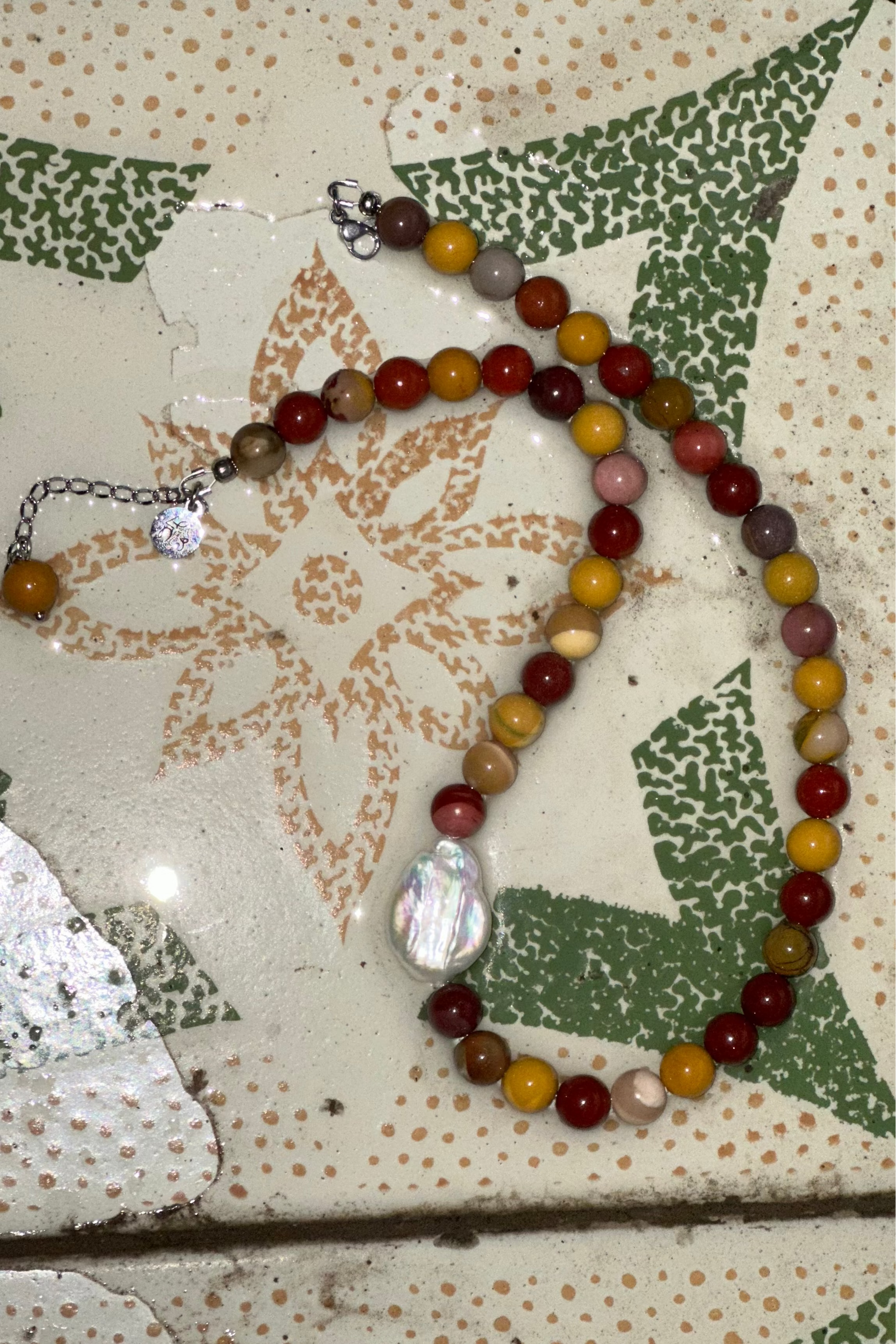 Multicolored beaded necklace on a textured surface with floral patterns