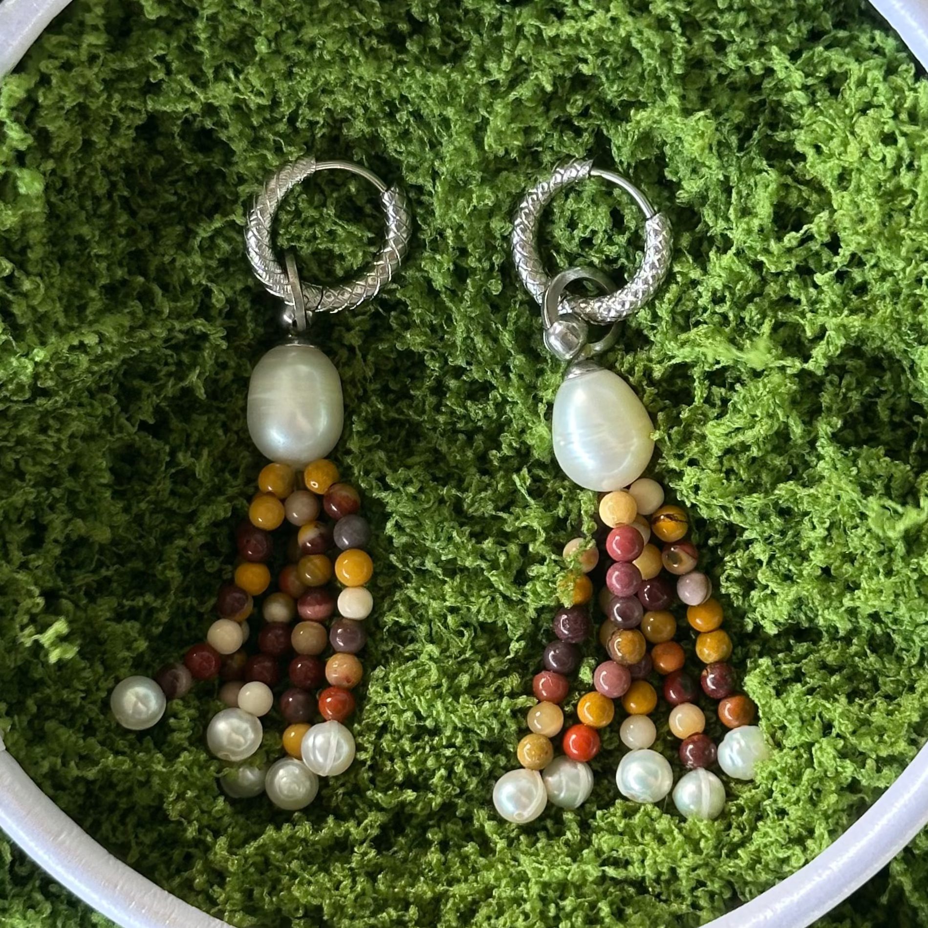 Pair of beaded earrings on a green moss background