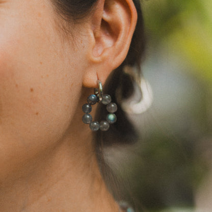 Close-up of a woman wearing earrings and a necklace with a blurred natural background