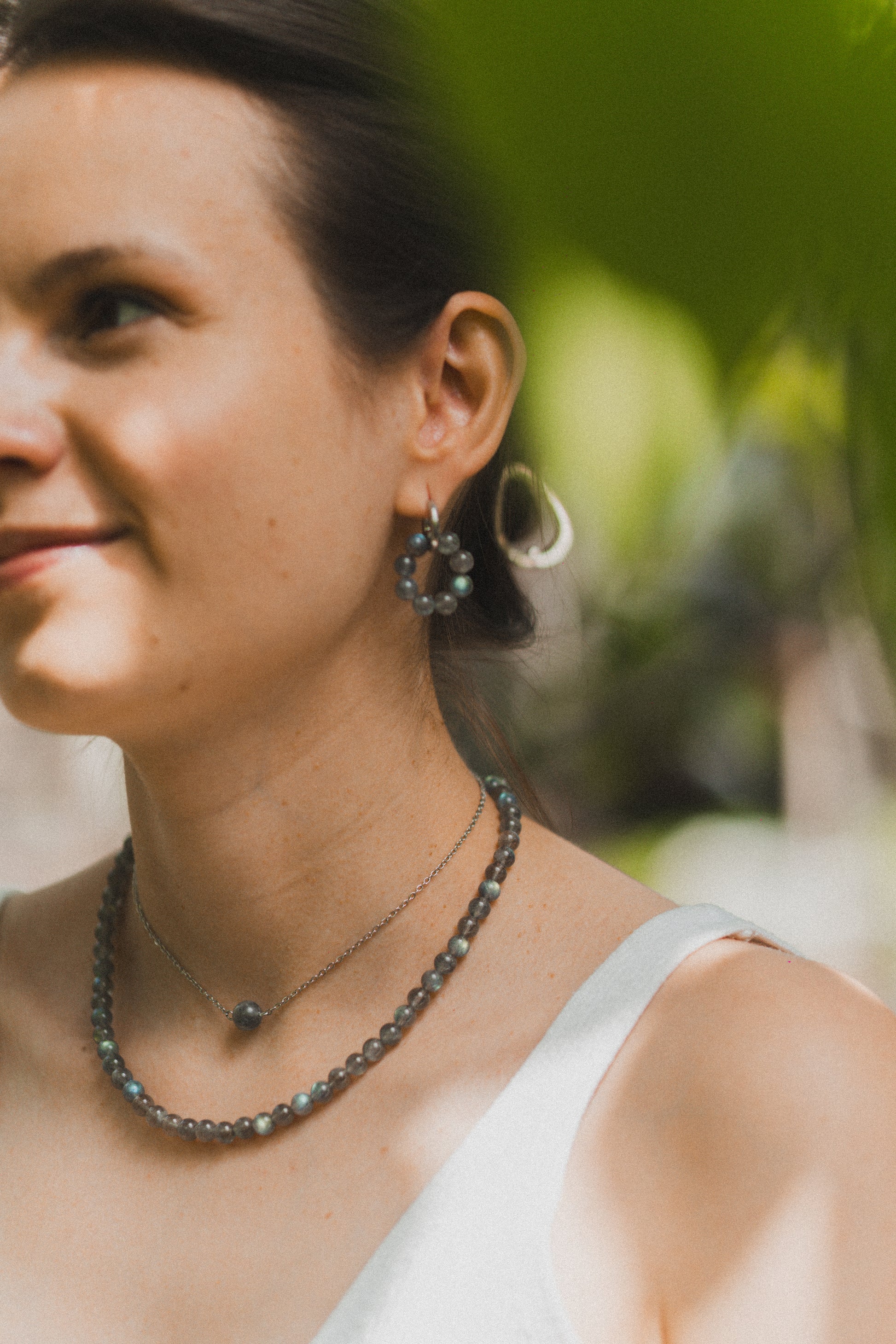 Woman wearing earrings and a necklace with a blurred natural background