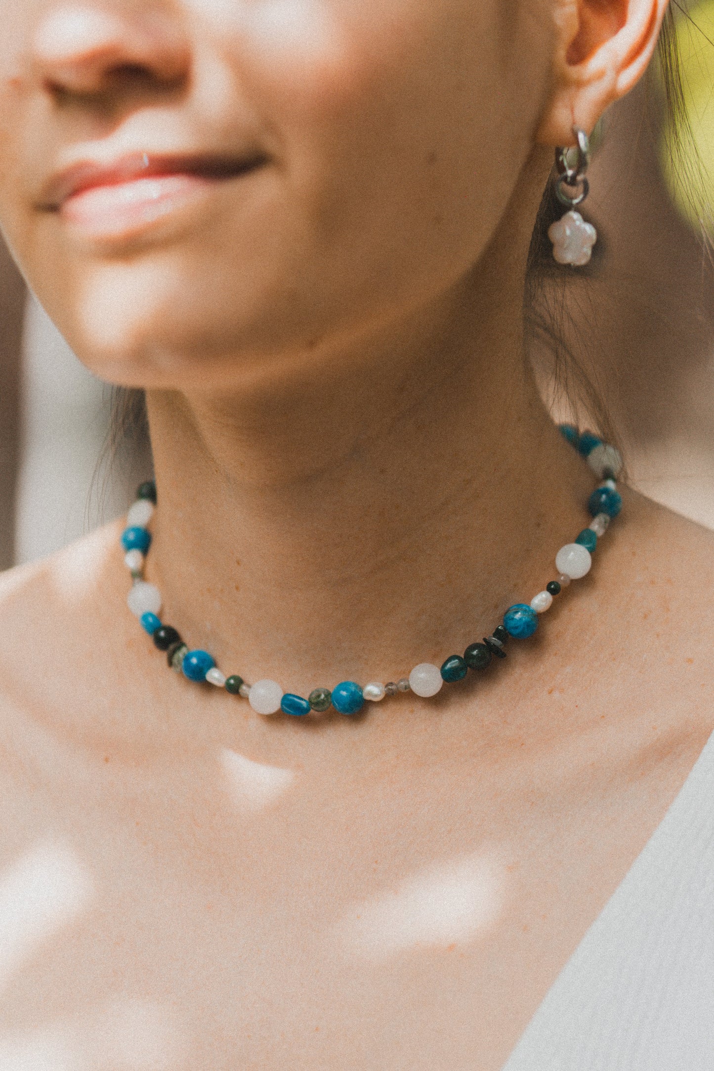 Close-up of a woman wearing a beaded necklace with a blurred background