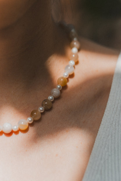 Close-up of a person wearing a beaded necklace with a blurred background