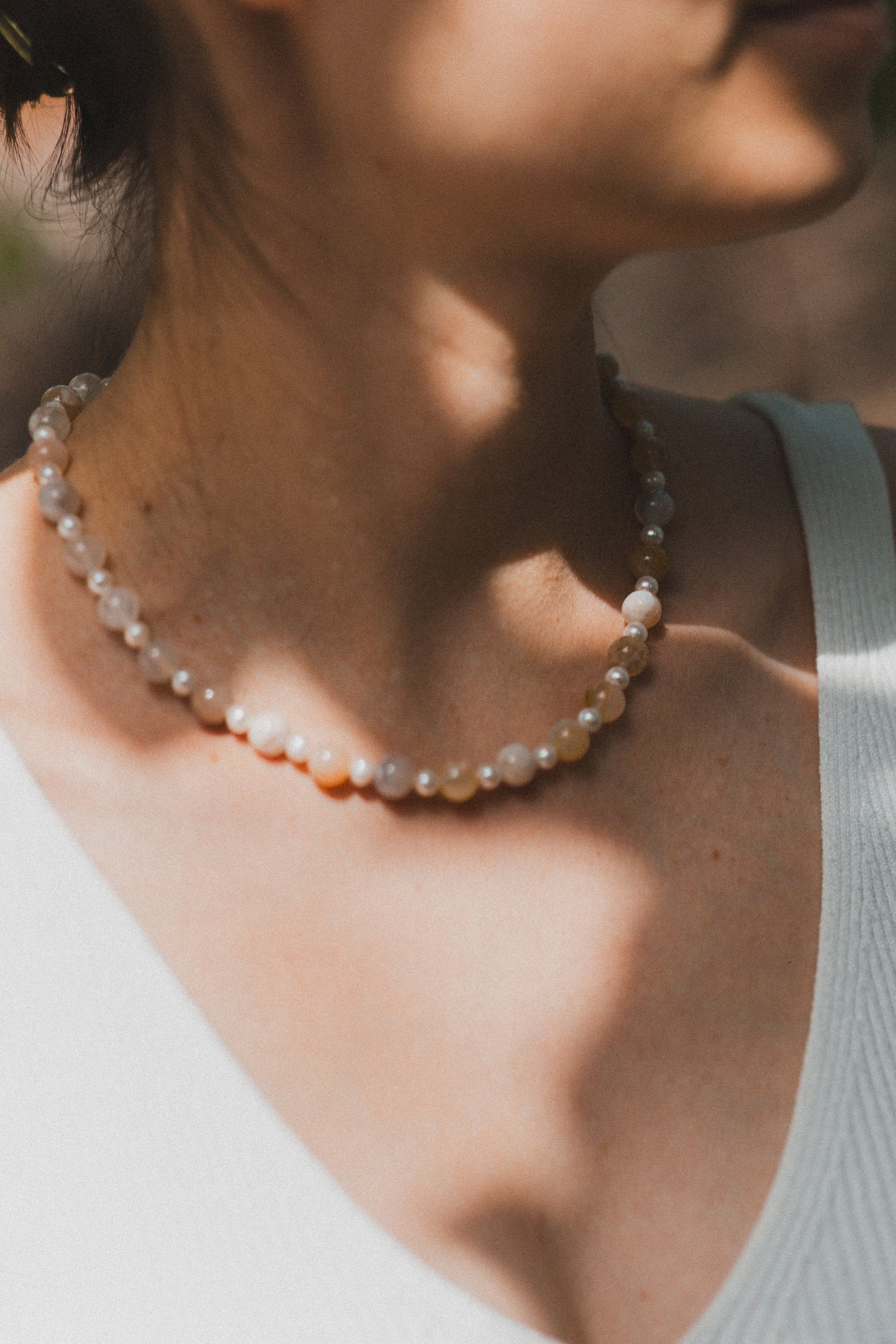 Close-up of a person wearing a pearl necklace with a blurred background