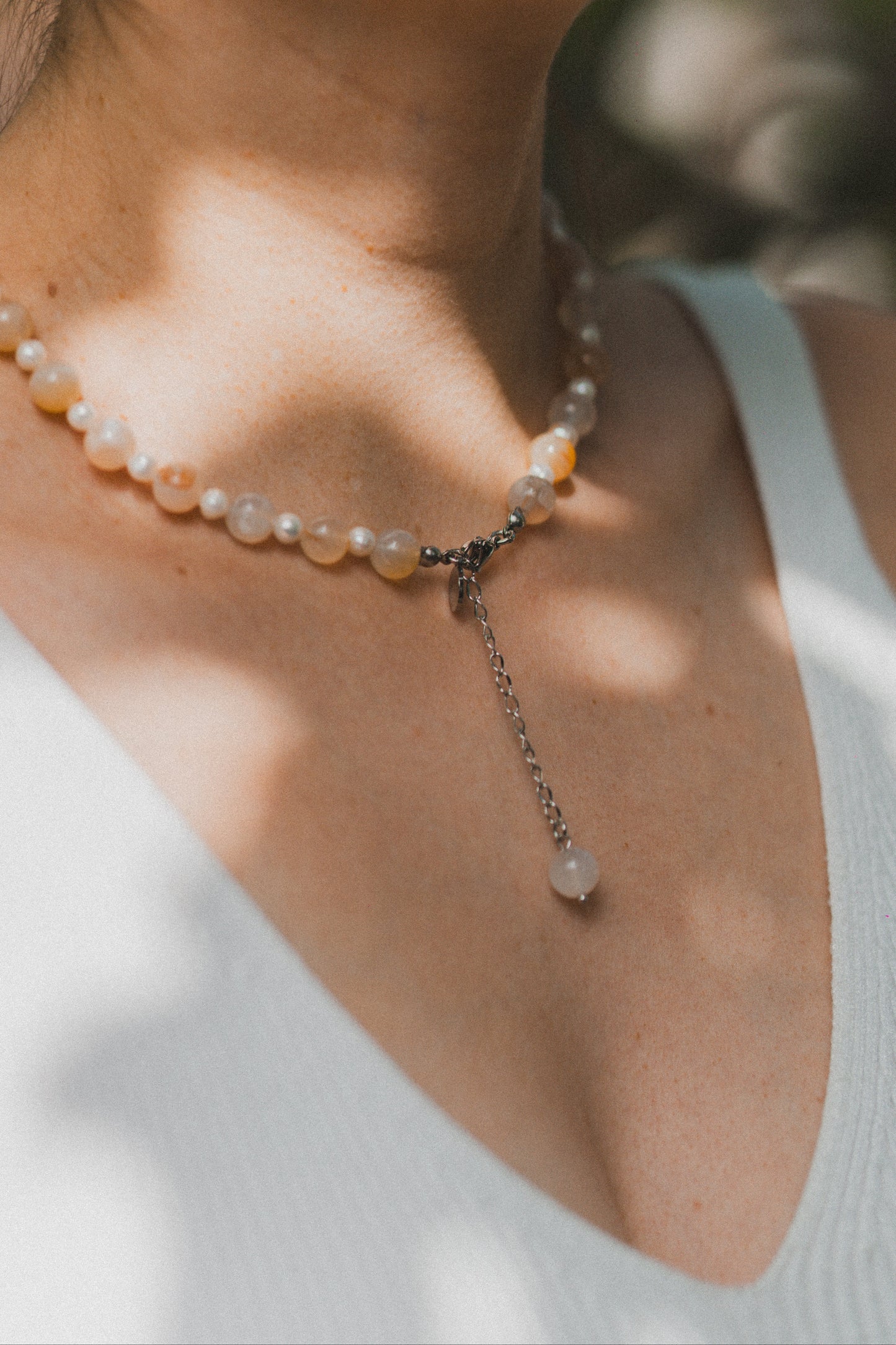 Pearl necklace worn by a person with a blurred natural background