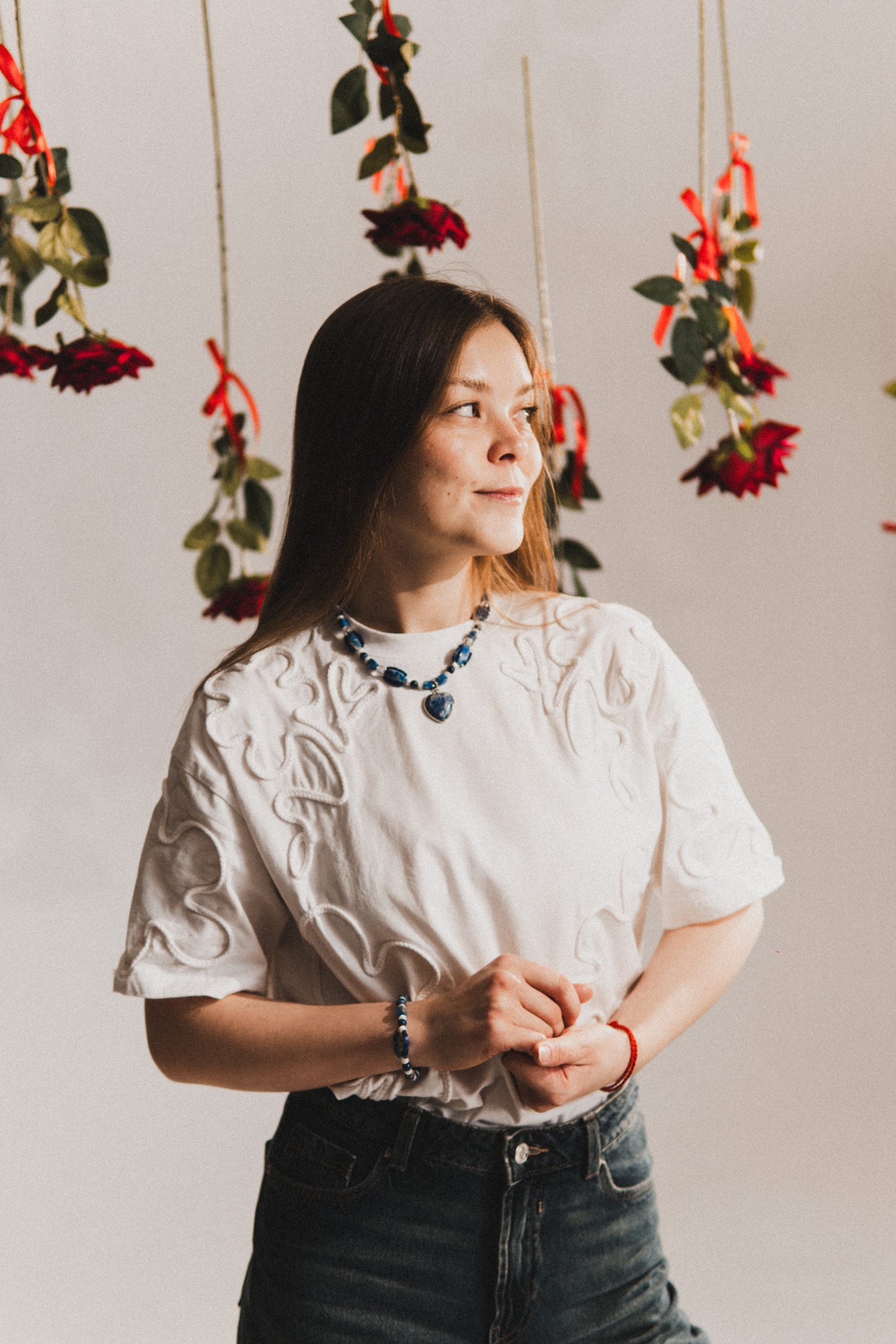 Woman standing in front of hanging floral decorations with red ribbons.