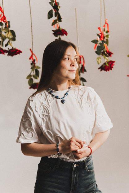 Woman standing in front of hanging floral decorations with red ribbons.