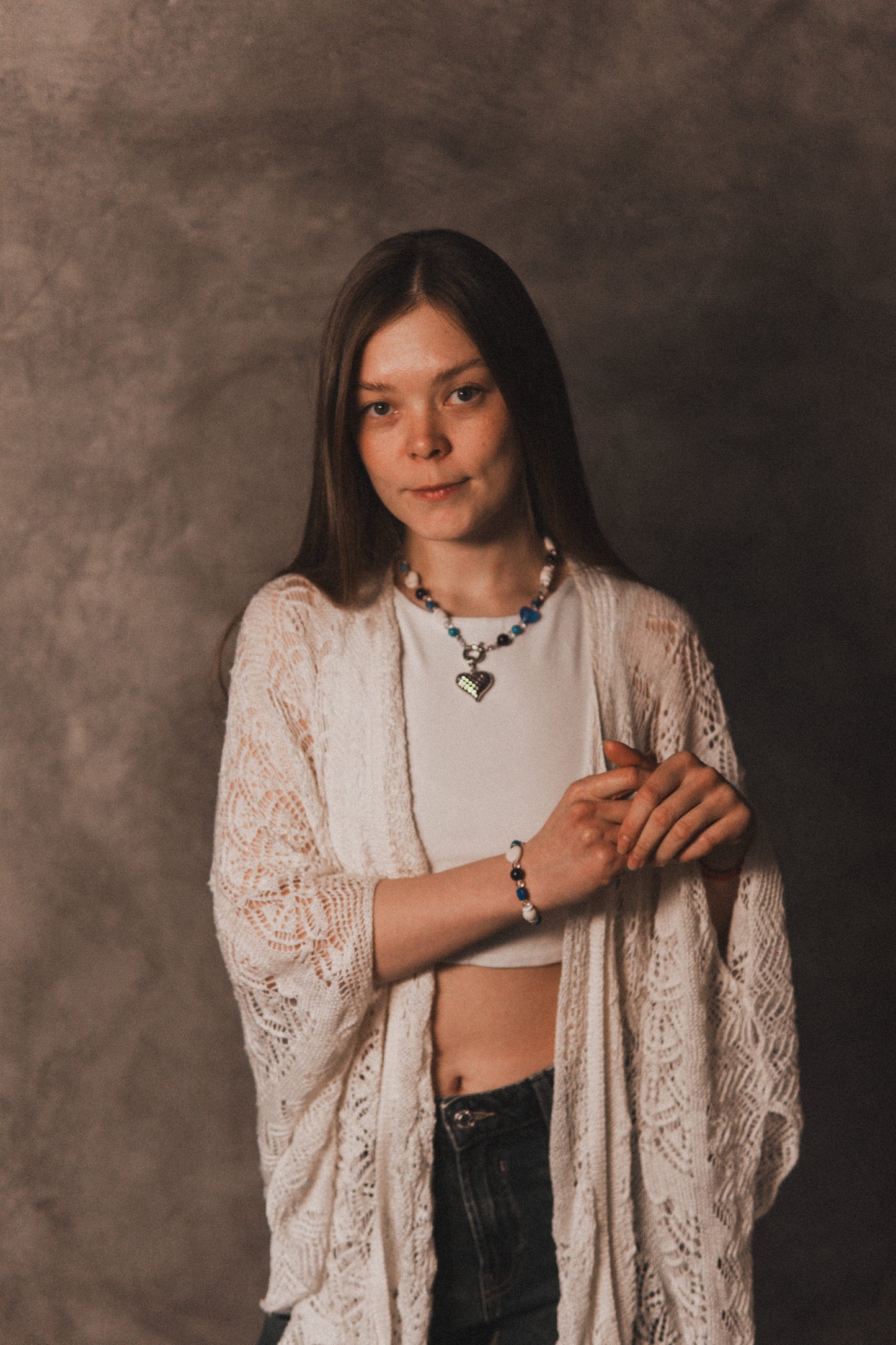 Woman wearing a white lace cardigan over a white shirt with a neutral background